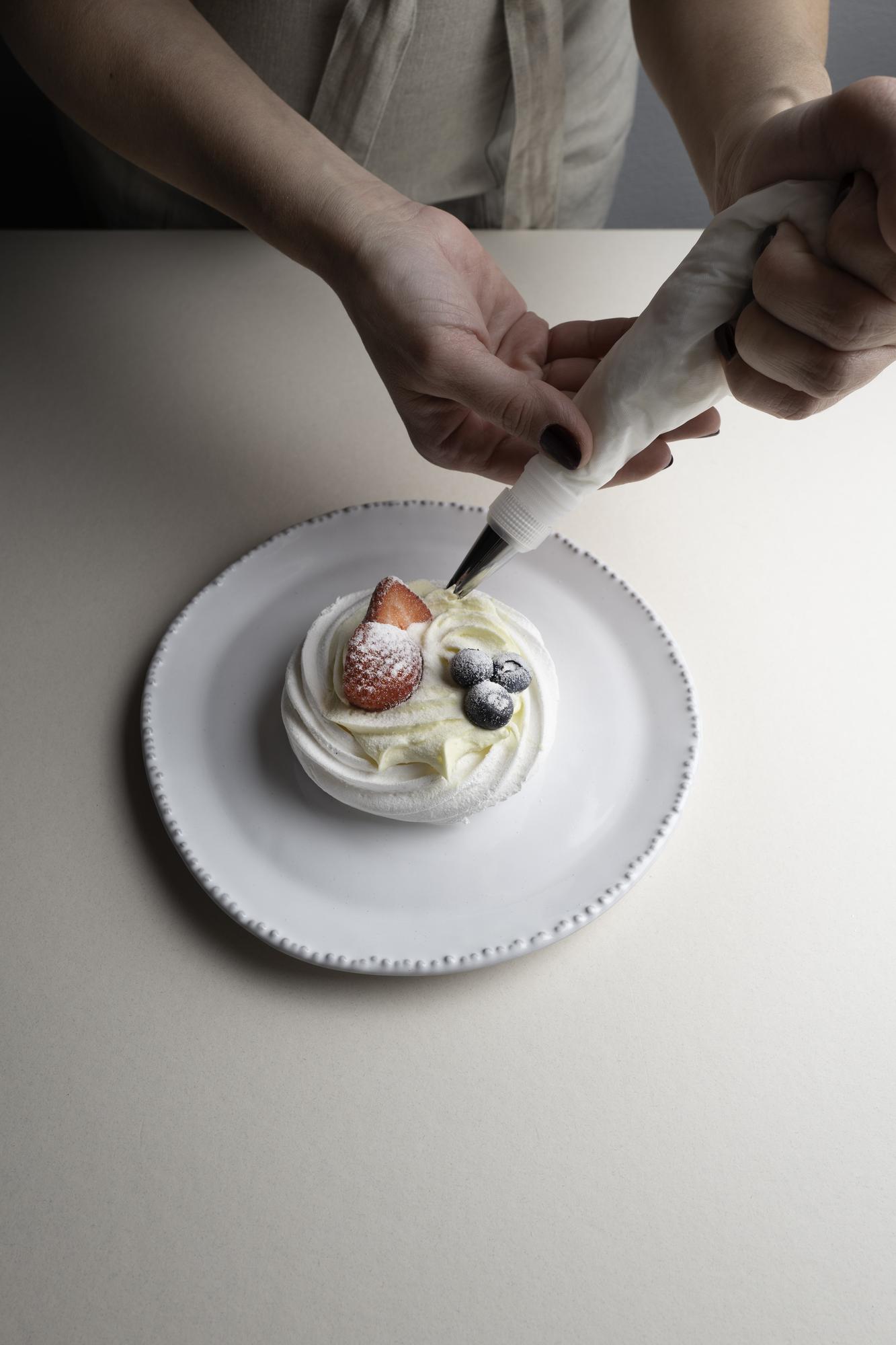 Hands preparing plated dessert in studio